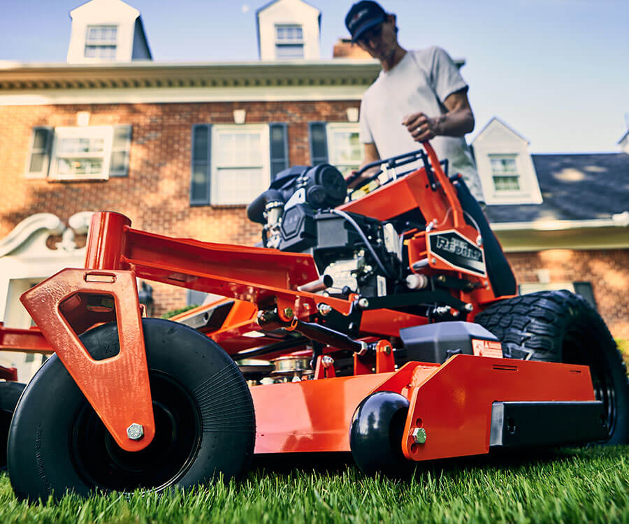 Homeowner maintaining a residential lawn with a Bad Boy Stand-On mower.