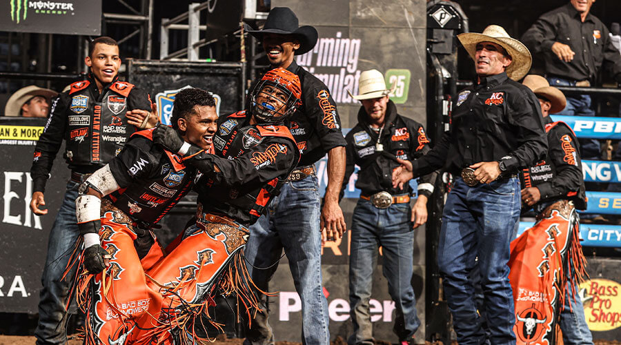 KC Outlaws teammates celebrating a successful ride during a Professional Bull Riders Team Series competition.