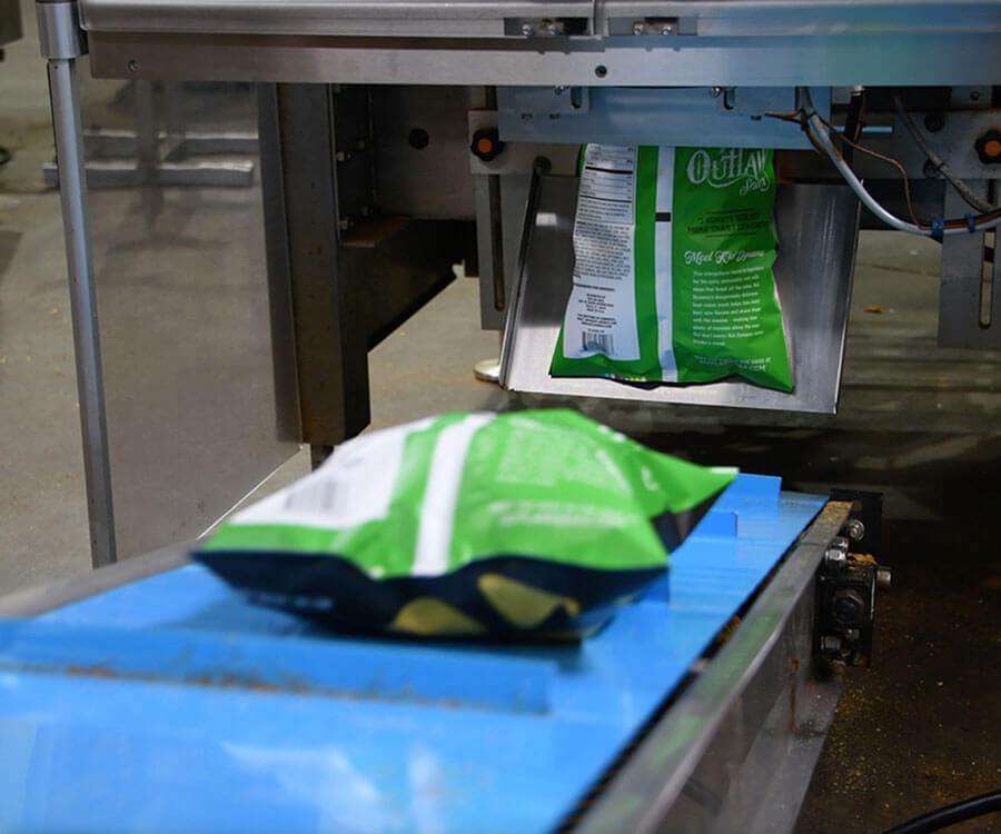 Outlaw Snax snack bags moving through the packaging process at the Ocala, Florida manufacturing facility.
