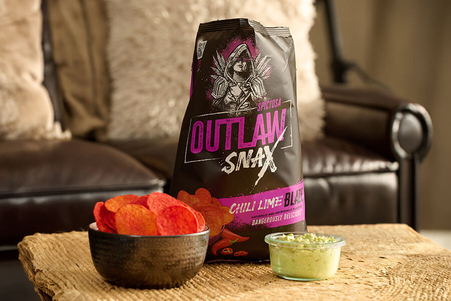 Outlaw Snax Chili Lime Blaze flavored tortilla chips served with guacamole dip for snacking.