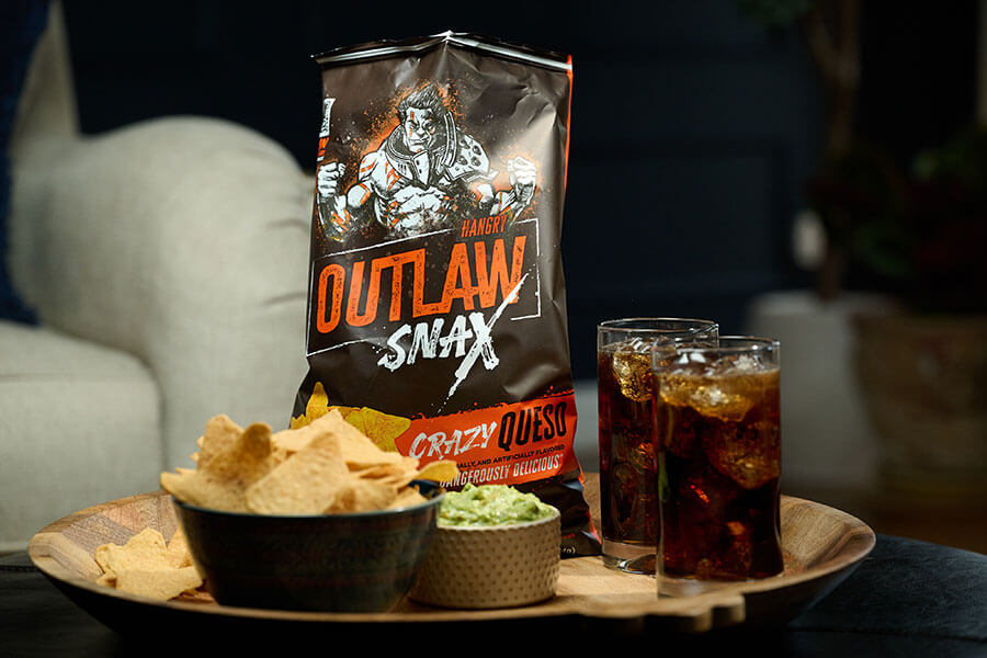 Outlaw Snax Crazy Queso flavored tortilla chips served with guacamole dip and drinks for snacking.